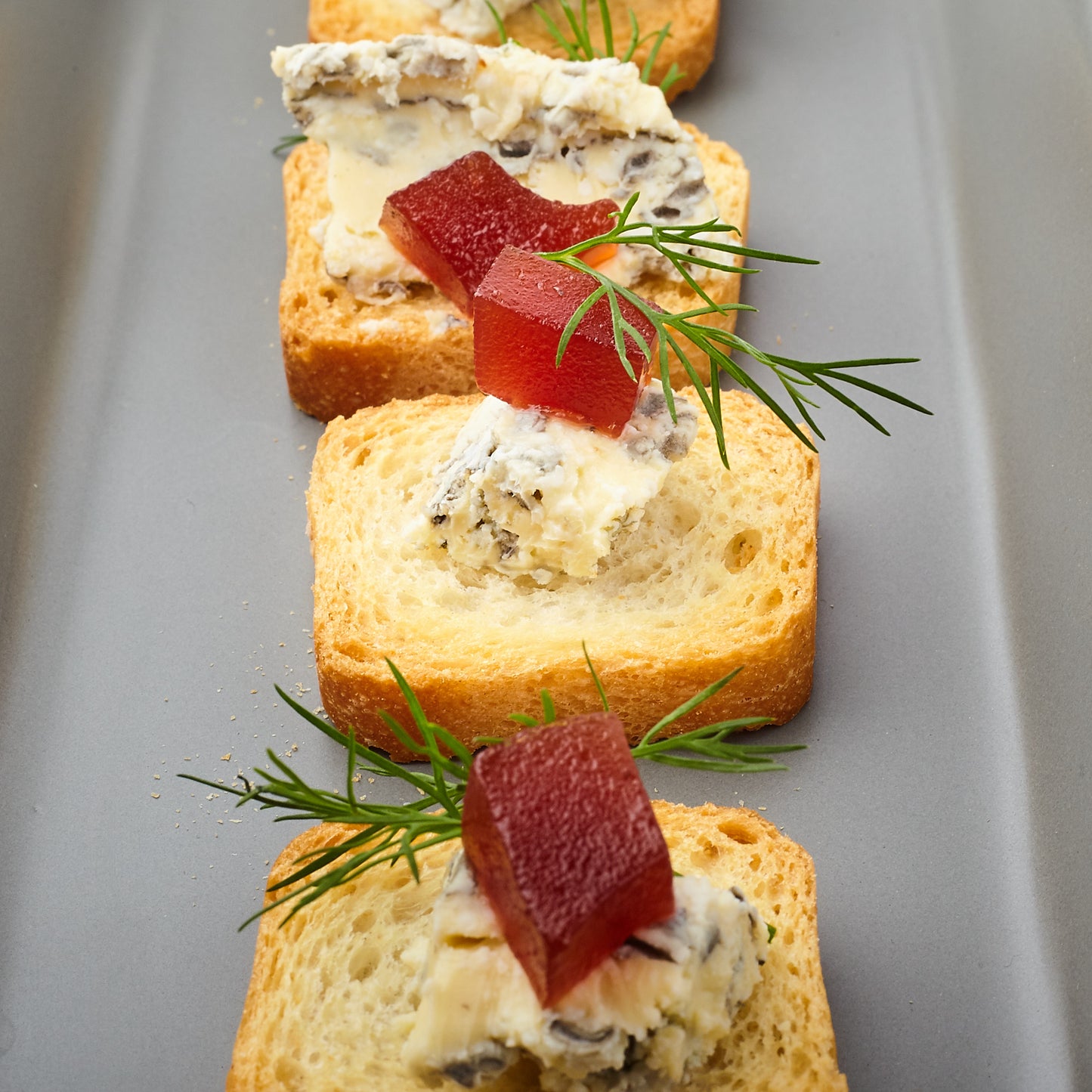 Quince and costello blue cheese on gluten free melba toast garnished with dill for aromatics.