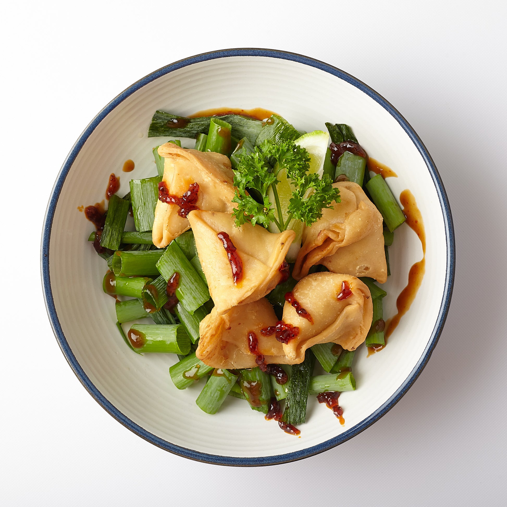 Vegetarian samosa on a bed of aromatic spring onions. Dash of Hot Rodeo Chilli Jam will make your guests come back for more!